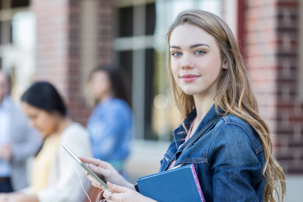 istock Portrait of teenage girl using digital tablet between classes 908148122