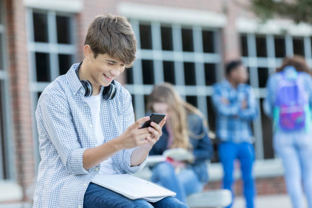istock Teenage boy enjoys texting while waiting for school bus 908148132