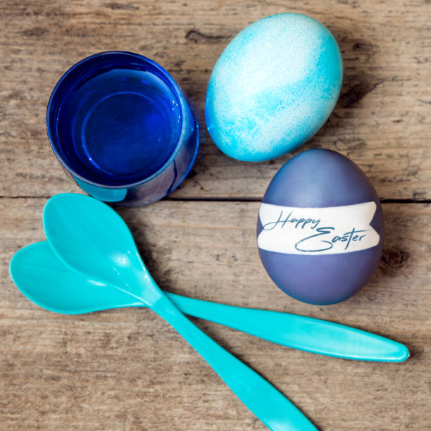 blue greeting card with easter eggs, egg spoons and egg dyes, english text happy easter - nodoby imagens e fotografias de stock