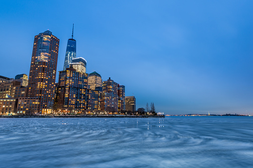 Ice swirls on the Hudson River during long exposure of Battery Park City and One World Trade Center in Lower Manhattan's downtown business district.