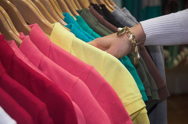 Woman looking through many colors of collared shirts