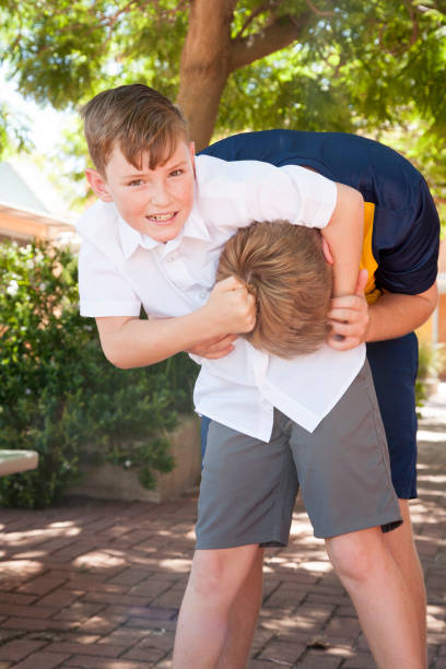 School Days Two school boys, one teenager one 10 year old in the schoolyard, Australia schoolyard fight stock pictures, royalty-free photos & images