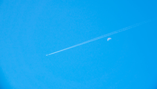 Airplane flying pass moon on day blue sky is beauty