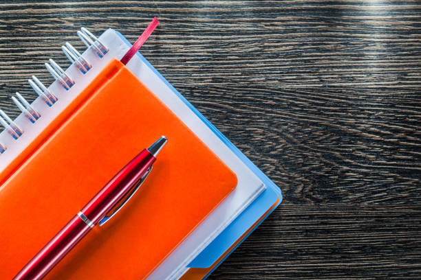 istock Notebooks ballpoint pen on wood board top view 908196236
