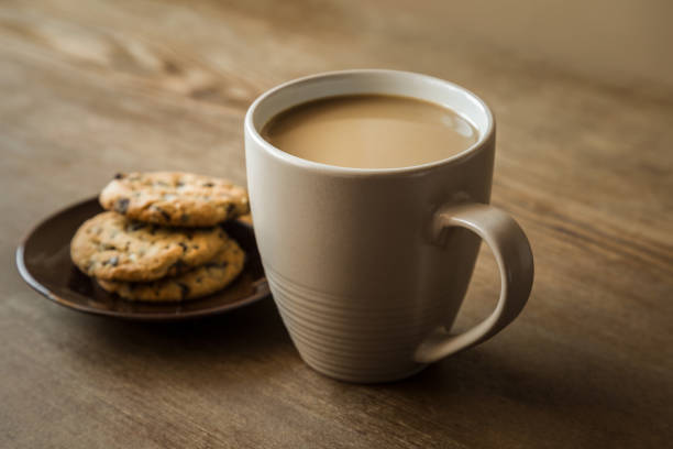 Cup of coffee with milk and cookies with chocolate pieces on the brown wooden table. Resting and enjoying time with coffee and sweets. Drink and snack concept. Cup of coffee with milk and cookies with chocolate pieces on the brown wooden table. Resting and enjoying time with coffee and sweets. Drink and snack concept. decaffeinated stock pictures, royalty-free photos & images