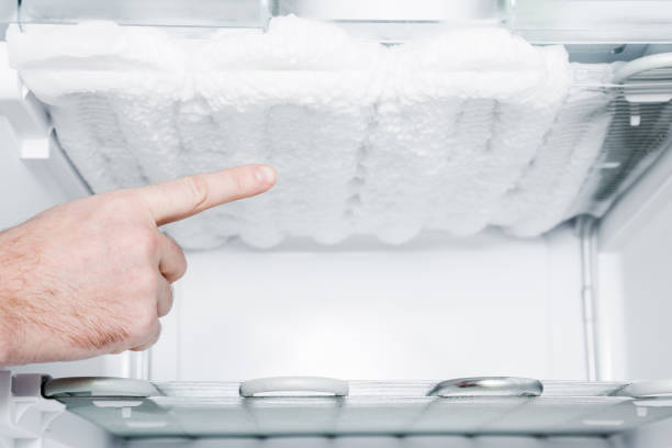istock Man's hand pointing to the frozen ice in the empty freezer. Problem and solution concept. 908200566