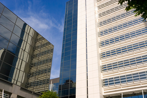 A glass fronted office building with the reflections of surrounding buildings in the windows.