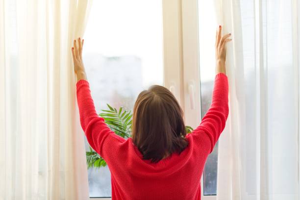 istock Woman looks out the window, opens the curtains. 908204994