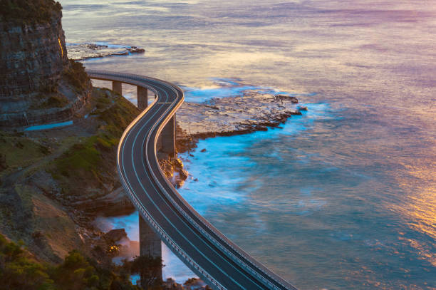istock Aerial view of bridge along cliff edge and ocean 908207040