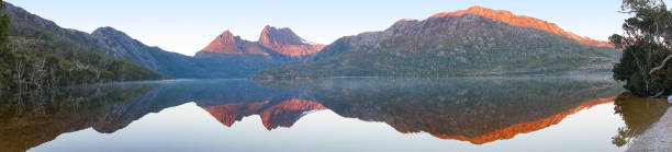 istock Beautiful panorama of mountain range reflected in lake on sunrise 908210486