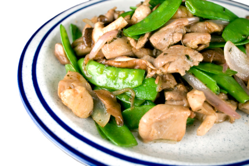 Stir fry with chicken, red paprika, mushrooms and chives in frying pan. Asian cuisine dish. Gray kitchen table background, top view, copy space