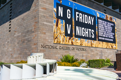 Melbourne, Australia - April 18, 2017: National Gallery of Victoria building with advertisement of Friday nights at gallery and fountain on sunny day