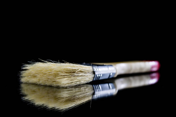istock A paintbrush for a painter on a glass table. Painting accessories in a mirror reflection. Black background. 908219696