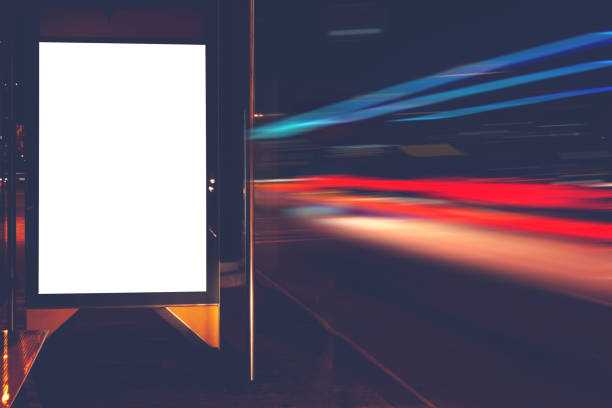 istock Blank electronic billboard with copy space for your text message or promotional content, public information board on bus stop, advertising mock up outdoors, empty poster in urban setting at night 908220100