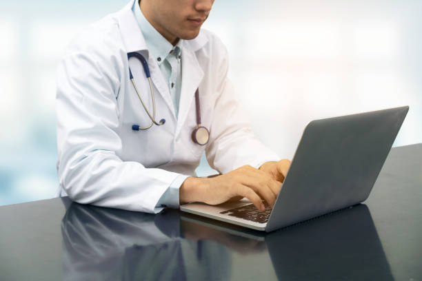 istock Doctor working on desk with laptop 908223410