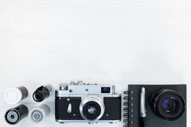 istock classic photo camera, negative film rolls, notebook and pen on white background with copy space 908224614