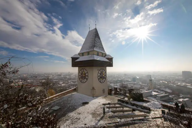 panorama of the  schlossberg hill  with the landmark clocktower uhrturm in winter, graz, austria