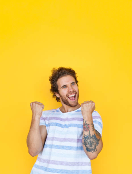 istock Victorious young man on yellow 908228348