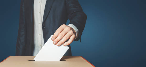 Man Voiter Putting Ballot Into Voting box. Democracy Freedom Concept Unrecognizable male voter holds in his hand a ballot above the ballot box election stock pictures, royalty-free photos & images