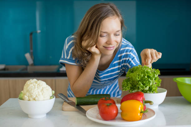 istock Pensive Young Woman Cooking Salad in Kitchen 908231780