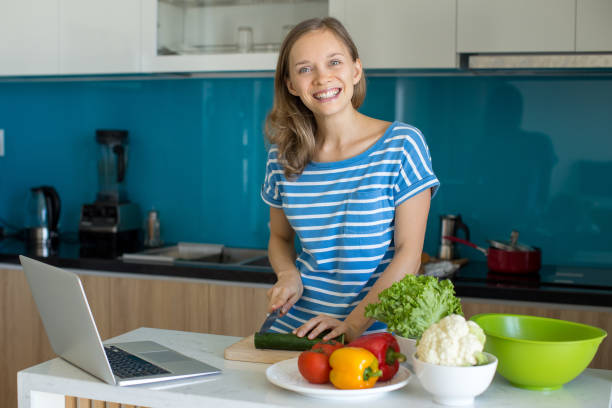 istock Smiling Young Woman Cooking Salad in Kitchen 908231796
