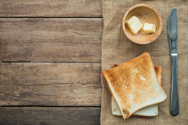 pane sandwich a fette tostate impilate con burro in ciotola di legno e coltello inossidabile su panno gunny sack su tavolo di legno - gunny sack foto e immagini stock
