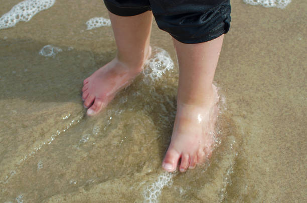 istock Child's legs in the water 908234890