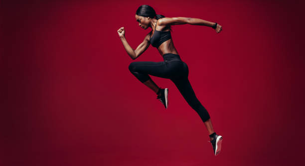 Sports woman running over red background Sports woman running over red background. Full length shot of healthy young african woman sprinting. carpet runner stock pictures, royalty-free photos & images