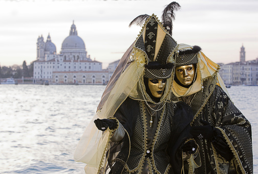 Venice, VE, Italy - February 13, 2024: couple of masked people with unrecognizable faces during the celebration of the Venice Carnival