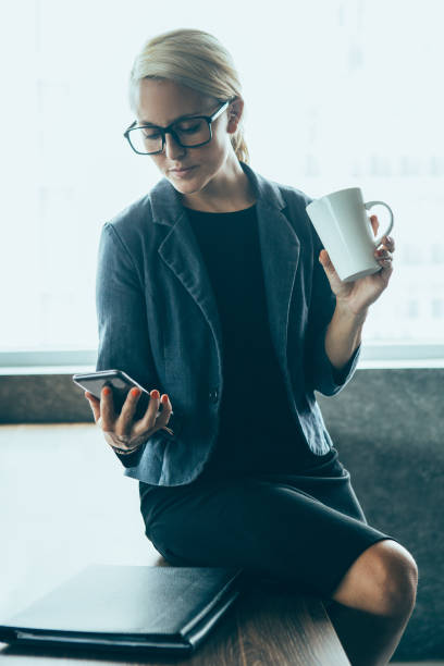 istock Serious woman reading message and drinking coffee 908244272
