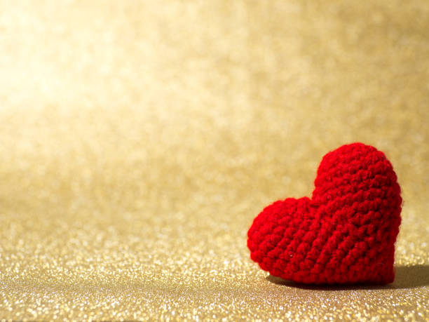istock Handmade red yarn heart on gold abstract background. Copy space for text, Valentines day, love concept and love background 908244302