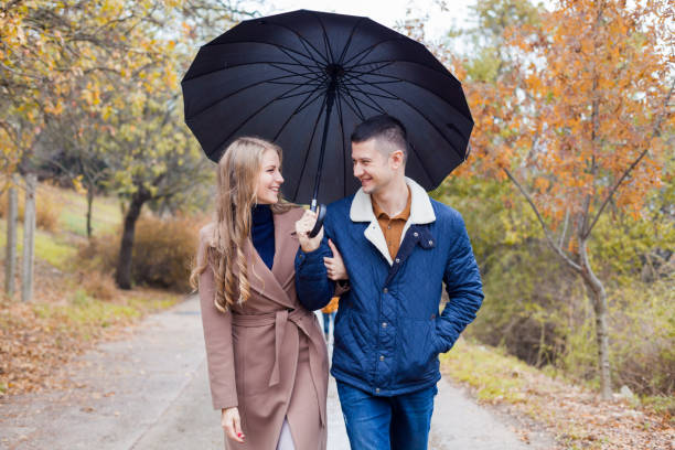 istock a guy with a girl go under umbrella rain 908244538
