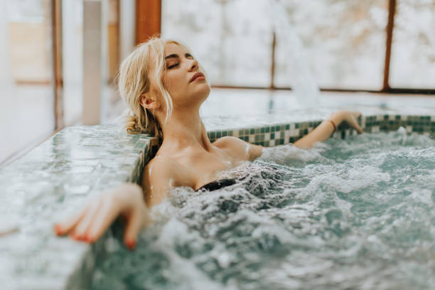 giovane donna che si rilassa nella vasca idromassaggio - trattamento di benessere foto e immagini stock