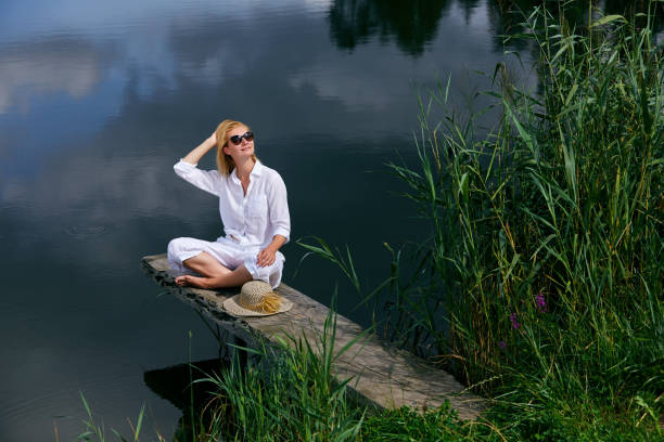 istock Young woman resting near lake 908249336