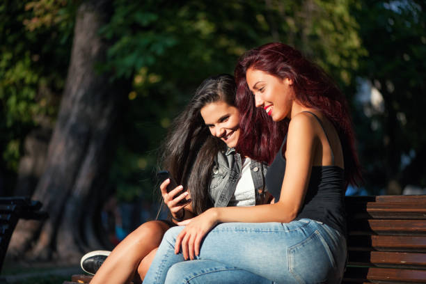 istock Two women with phone in the park 908251948