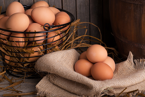 Brown chicken eggs in a basket and on a burlap cloth