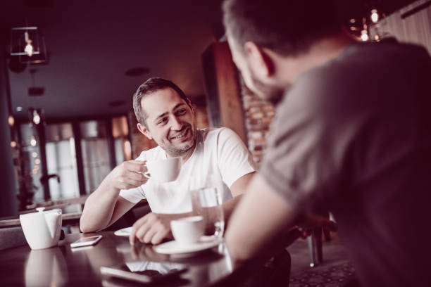 istock Two Smiling Friends Drinking Coffee and Socializing in a Coffee 908260054