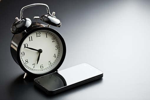 alarm clock with cellphone on black table