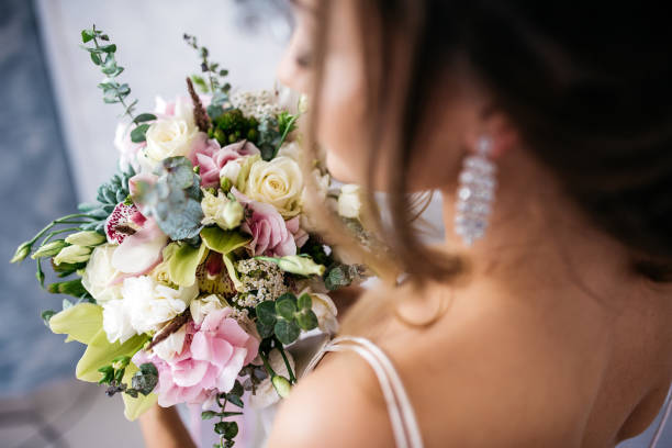 istock Bride with bouquet in hands, frame from behind shoulder. The background is blurred 908271738