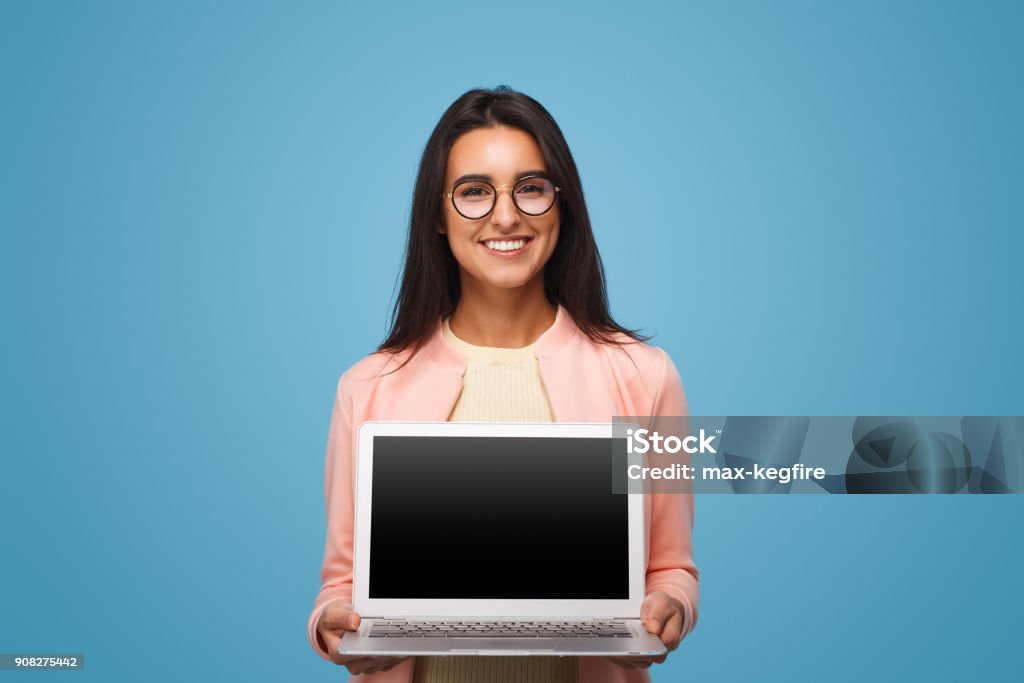 Happy business woman holding laptop Happy business woman holding laptop with empty black screen over blue background. Mexican girl with computer Laptop Stock Photo