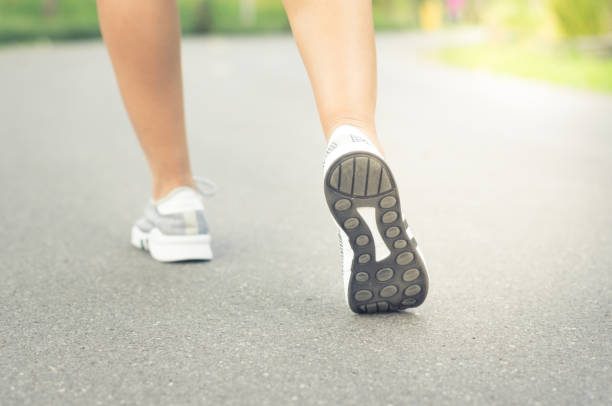 istock Female runner feet jogging on street. 908275834