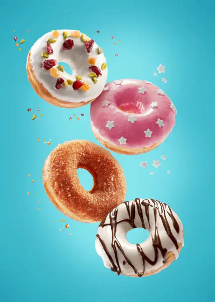 Photo of Donuts selection flying on blue background. Various doughnuts isolated on colorful background