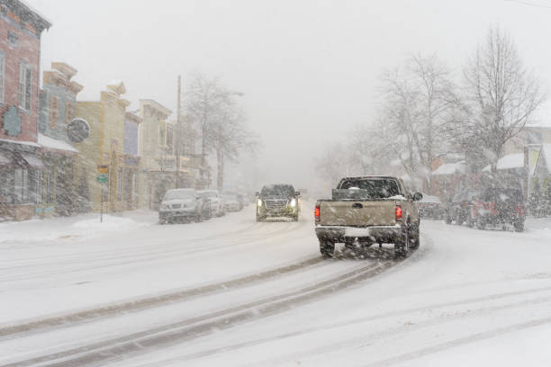 An intense snow storm in small town America.  Cars driving down the road of a small town in northern Michigan.