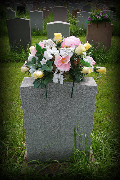 Artificial flowers display vibrant colors at grave marker, creating peaceful tribute in well kept cemetery.
