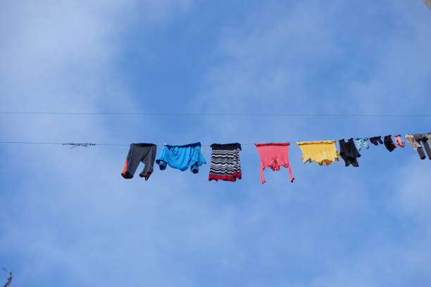 Senior man hanging laundry on a clothes line on a bright summer afternoon in Scotland