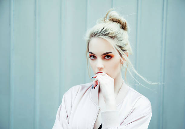 Portrait of young woman wearing bomber jacket Young blonde woman wearing bomber jacket outdoor portrait hair bun stock pictures, royalty-free photos & images