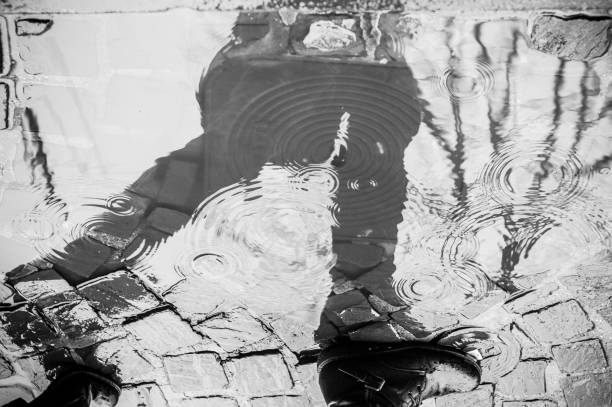istock reflection of a person walking in a puddle in the rain 908303868