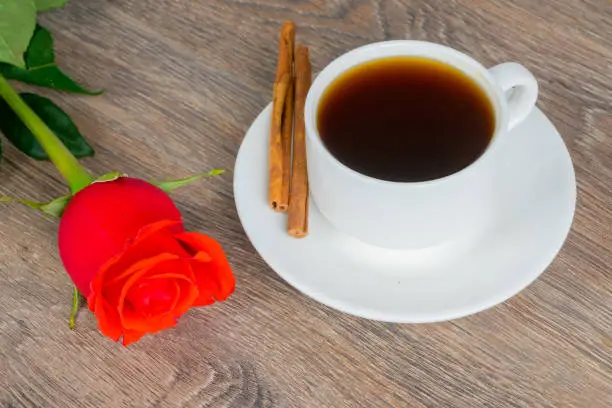 red rose with coffee cup on wooden table