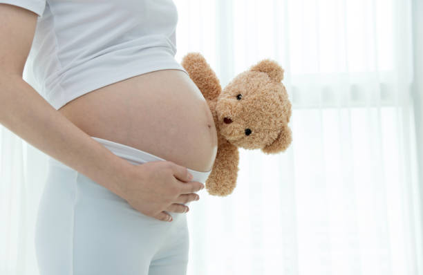 istock Pregnant woman holding a teddy bear 908314826