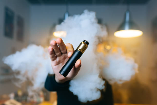 증기의 구름을 통해 그의 뻗은 손에 젊은 수염 남자 쇼 vaping 장치. 선택적 초점입니다. vaping 개념입니다. 공간 복사 - infused oil 이미지 뉴스 사진 이미지